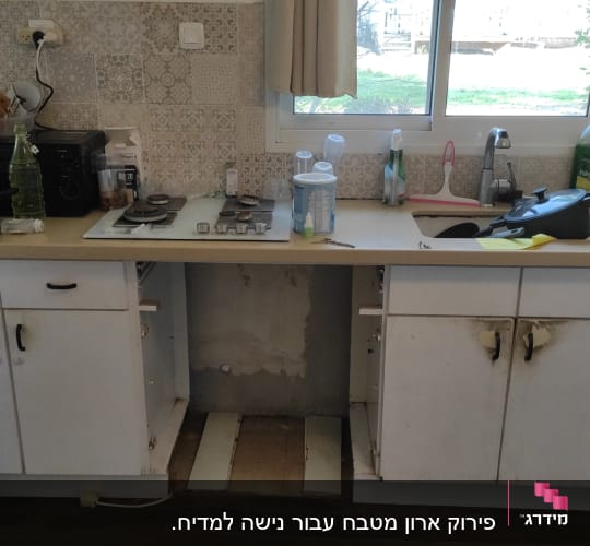 מטבח עם ארונות פתוחים, משטח עבודה וכלים שונים